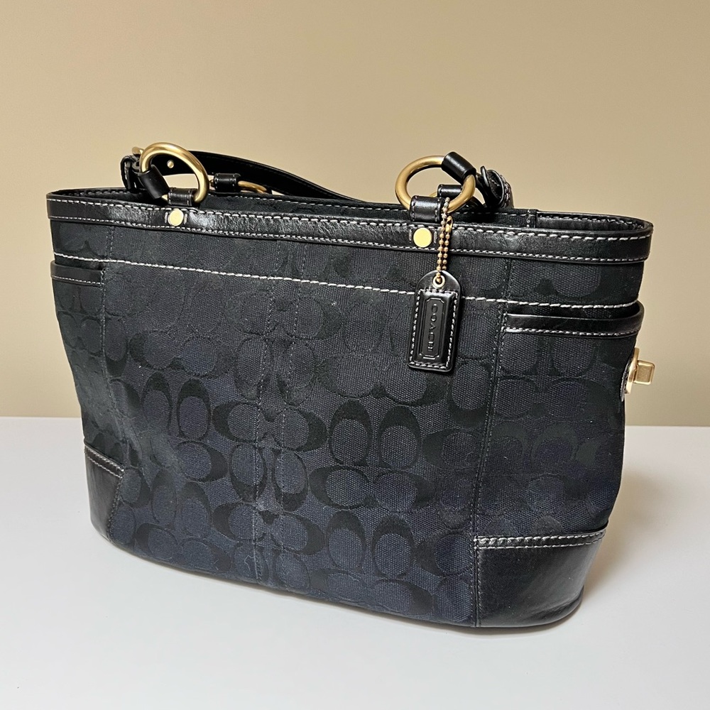 Coach F11237 Black Signature Jacquard & Leather Tote is being used.